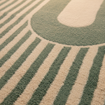 Close-up of a textured area rug with a modern geometric pattern featuring alternating vertical stripes in sage green and cream.