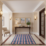 A rectangular area rug with a pink and navy blue geometric checkered pattern is displayed in a beautifully styled entryway with beige walls, a dark wood console table, and wall sconces.