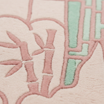 Close-up of a textured fabric surface with a stylized embroidered or woven pattern in blush pink and mint green.