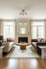 Living room with a fireplace, sofa, moroccan shaggy rug, and coffee table in a well-lit room.