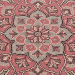 A close-up of a traditional patterned rug featuring a central floral medallion in dusty pink, sage green, and cream.