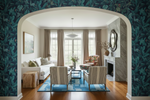 Living room with floral wallpaper, sofa, blue rug, chairs, and a fireplace.