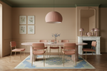 Dining room with a blue rug, pink pendant light, round table, and chairs.
