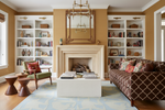 Living room with a fireplace, blue rug, bookshelves, and patterned sofa.