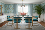 Elegant dining room with teal chairs, gold table, blue rug, and floral centerpiece.