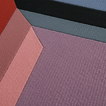 A close-up of textured fabric or carpet samples arranged in geometric color blocks, including dusty purple, muted pink, slate blue, black, and a small red section.