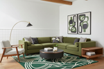 Modern living room with green sectional sofa, armchair, and abstract art on the wall.