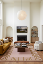 Modern living room with pink rug, yellow sofa, white armchair, coffee table, and decorative elements.