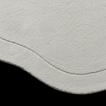A close-up of a textured off-white or cream fabric surface with a curved edge, shown against a solid black background.