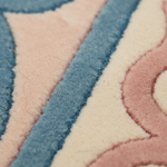 Close-up of a plush textured rug with a geometric pattern in dusty blue, soft pink, and cream.