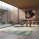 A modern living room scene featuring a multicolor geometric patterned area rug on a concrete floor, next to a black leather chaise lounge and a brick wall with a large abstract painting.
