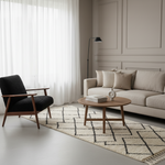 A styled living room scene featuring a black textured armchair, a beige sofa, a round wooden coffee table, a black floor lamp, and a cream and black patterned area rug on a light gray floor.