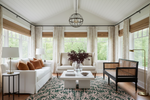 Living room with white sofa, armchair, coffee table, green pink rug, and decorative elements.