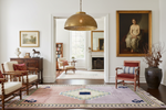 Living room with a patterned rug, chairs, and a painting on the wall.