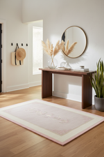 Room interior with a wooden console table, pink rug, mirror, and decor items.