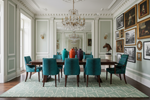 Dining room with teal chairs, rug, a wooden table, and decorative wall art.