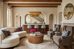 Modern living room with a curved sofa, gray rug, coffee table, and decorative pillows.
