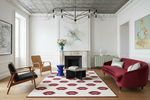 Modern living room with a red sofa, patterned lip red rug, and decorative elements.