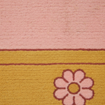Close-up of a textured rug with a pink upper section, a mustard yellow lower section, and a pink flower motif outlined in burgundy.