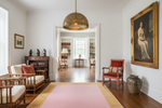 Living room with wooden furniture, pink rug, and decorative wall art.
