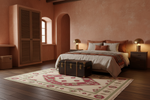 Cozy bedroom with pink walls, bed, tribal rug, and wooden floor.