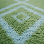 Close-up of a plush rug with a geometric diamond pattern in light green and pale blue, showing the soft pile texture.