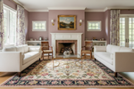 Living room with white sofas, a fireplace, and decorative floral beige and black rug.
