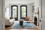 Living room with a blue and pink blue patterned rug, white sofa, and wooden chair.