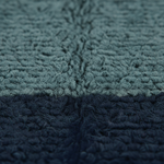 Close-up of a textured, loop-pile fabric or rug in a two-tone color-blocked design, transitioning from a muted slate blue-gray at the top to a deep navy at the bottom.