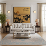 A large framed vertical art print featuring a golden Japanese landscape with mountains, trees, and calligraphy, displayed on a white wall above a white sofa in a modern, well-lit living room.