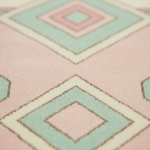 Close-up of a textured rug with a geometric diamond pattern in pastel pink, mint green, cream, and light blue.
