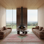Modern living room with a fireplace, pink green moroccan shag rug, and large windows overlooking a scenic view.