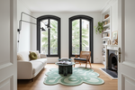 Modern living room with white sofa, green rug, and large windows.