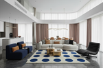 Modern living room with a white sofa, blue armchair, and decorative blue rug.