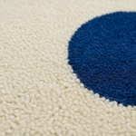 Close-up of a textured rug with a cream background and a large dark blue circular motif.