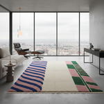 Modern living room with a colorful geometric rug, sofa, and cityscape view.