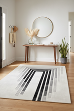 Modern interior with a contemporary rug featuring black and gray stripes, a wooden console table, and decorative items.