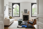 Modern living room with white sofa, black and white rug, armchair, and decorative elements.