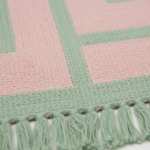 Close-up of the pink and sage green stripes and fringe on the Moss Velvet Reverie rug
