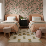 A styled bedroom interior with two single beds, peach upholstered bedsides, striped pillows, matching peach bedding, a floral wallpaper wall, a patterned rug, woven ottomans, a black nightstand, and a pink backpack on the floor.
