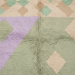 A close-up of a plush, textured rug featuring a pastel geometric diamond pattern in sage green, lavender purple, beige, and mint green.