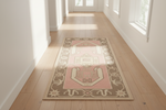 Decorative tribal pink runner rug on a wooden floor in a bright room with large windows.