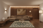 A modern living room featuring a beige sectional sofa, a patterned blue and beige area rug, a wooden coffee table, and a large framed palm tree artwork on a wood-paneled accent wall.