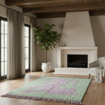 Living room with a green and purple rug, plant, and fireplace.