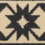 Close-up of a textured woven rug with a bold black geometric starburst pattern on a warm cream background.