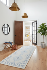 Modern interior with wooden floor, gray runner rug, and open door leading to another room.