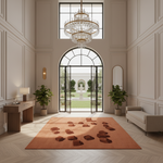 A large rectangular terracotta orange area rug with a pattern of small dark brown stones, displayed in a grand, elegant foyer with a chandelier, paneled walls, and a garden view.