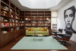Modern living room with blue rug,  bookshelves, green sofa, and stylish chairs.