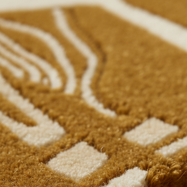 Close-up of a textured area rug with a geometric pattern in warm camel brown and cream.