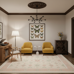 A styled interior room with two mustard yellow armchairs facing a small white side table, set on a large cream patterned area rug. A framed butterfly print hangs on the wall, with a floor lamp, wooden desk, chair, dark wood cabinet, and floral vase arranged around it.